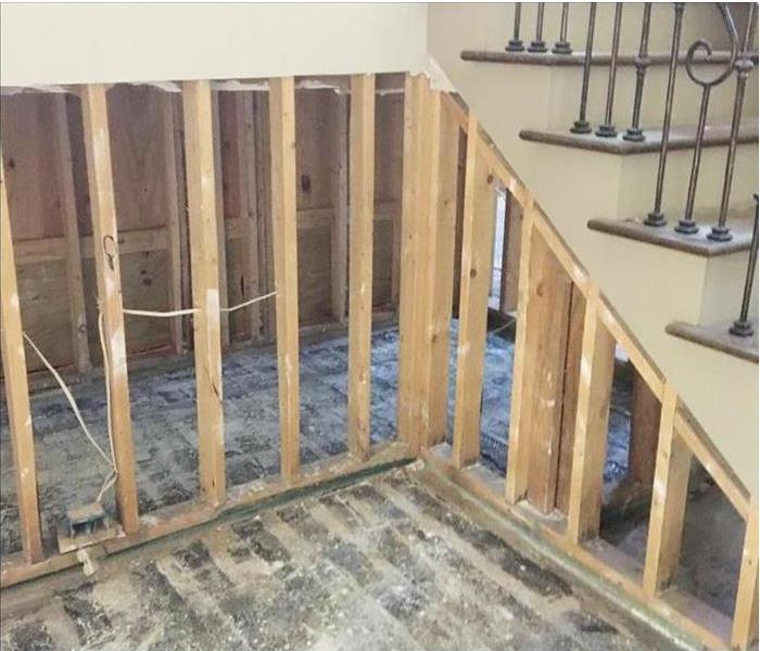 removed walls and flooring, showing studs by stairs