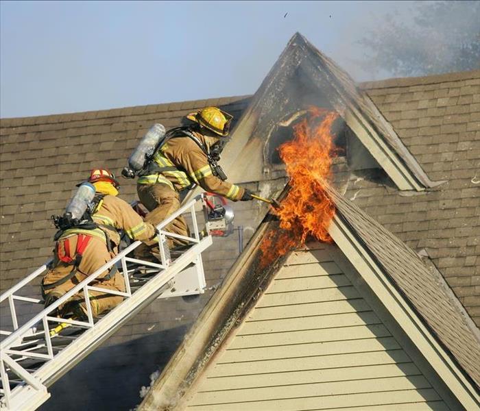 firemen on ladder at peak battling blaze